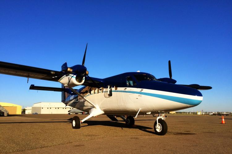 A twin-engine NOAA Twin Otter airplane parked on the ground at an aiport