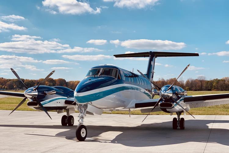 A small blue and white turboprop on the tarmac on sunny day