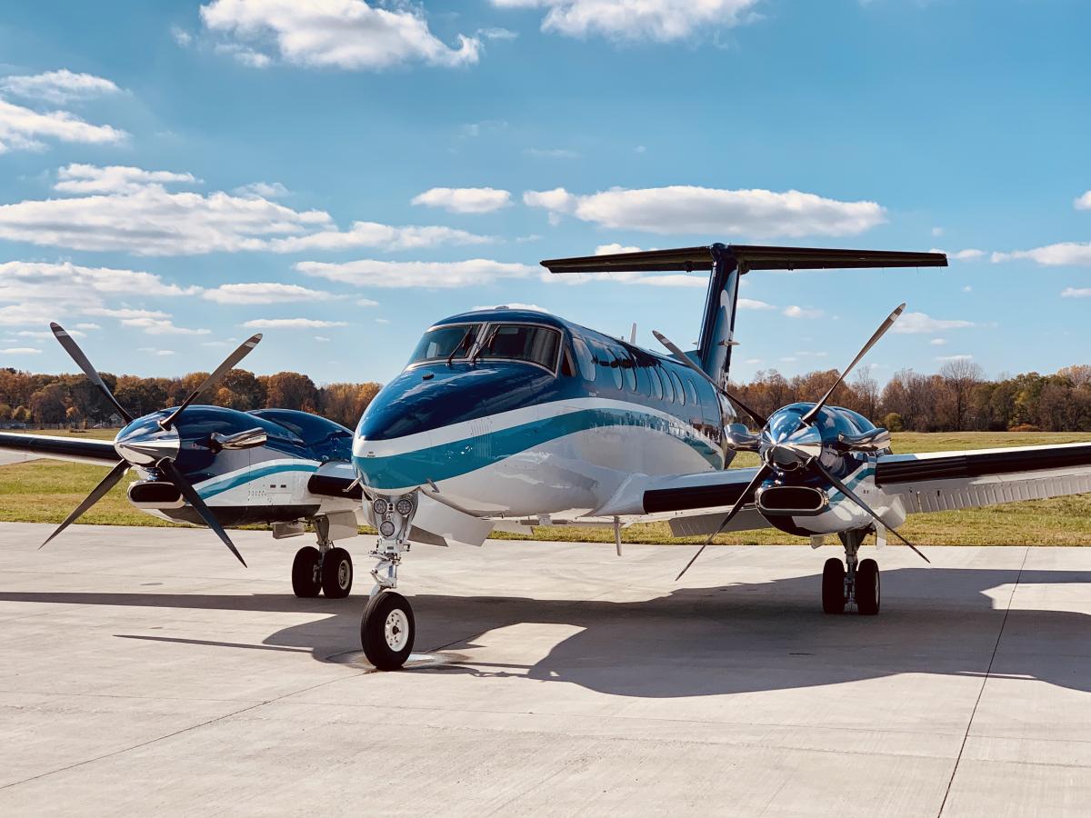 A small blue and white turboprop on the tarmac on sunny day