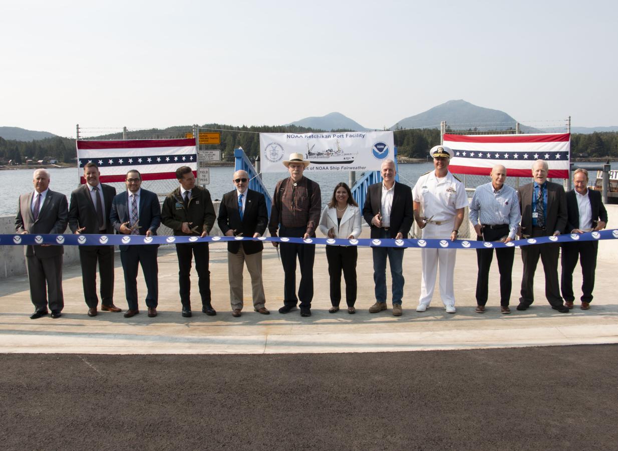 A long line of special guests, including NOAA Administrator Dr. Rick Spinrad (5th from the left), participate in a ribbon-cutting ceremony for the NOAA-renovated port facility in Ketchikan, Alaska, on August 21, 2023.