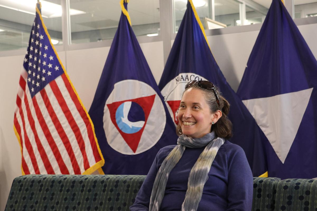 Alexis Gutierrez with flags in the background. Credit: NOAA/Eliza Mills