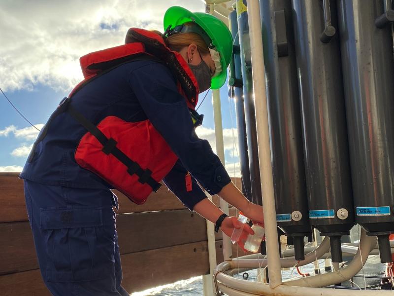 Lt. j.g. Edmonds is on the left collecting water samples from a CTD device on the right.