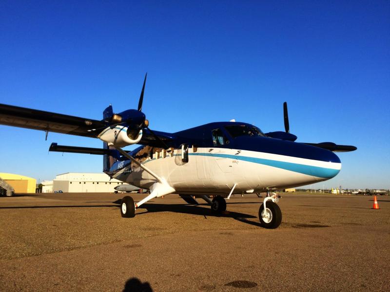 A twin-engine NOAA Twin Otter airplane parked on the ground at an aiport