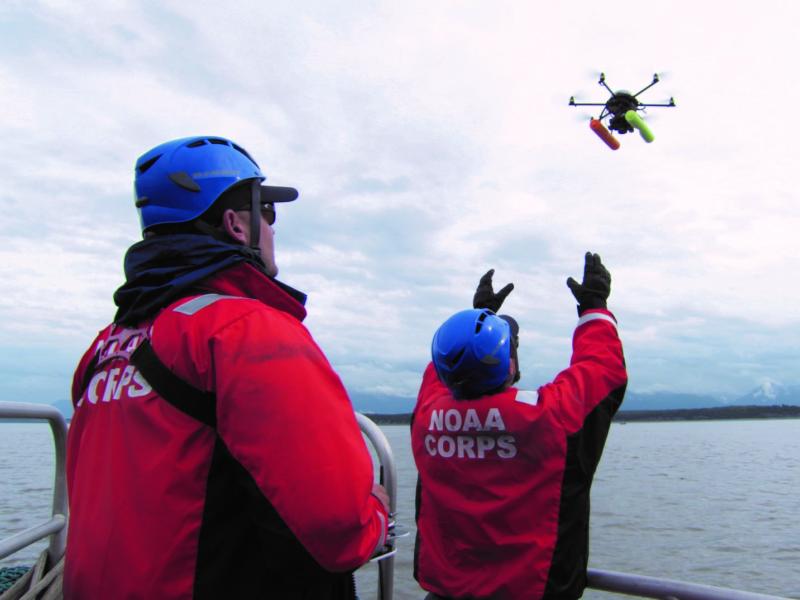 Two NOAA Corps officers launch a hexacopter drone into the air