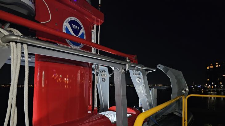 The red DriX uncrewed marine system sits in its gray gondola at night