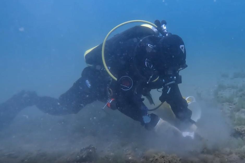 A scuba diver taking a sample from the bottom of a lake