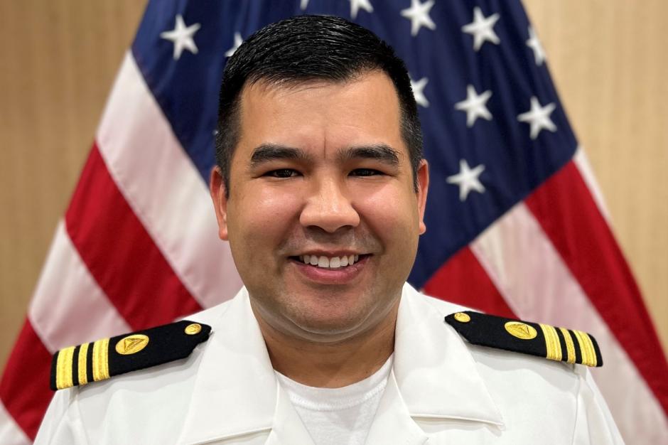 Lieutenant Commander Andrew Reynaga posed in front of the American flag.