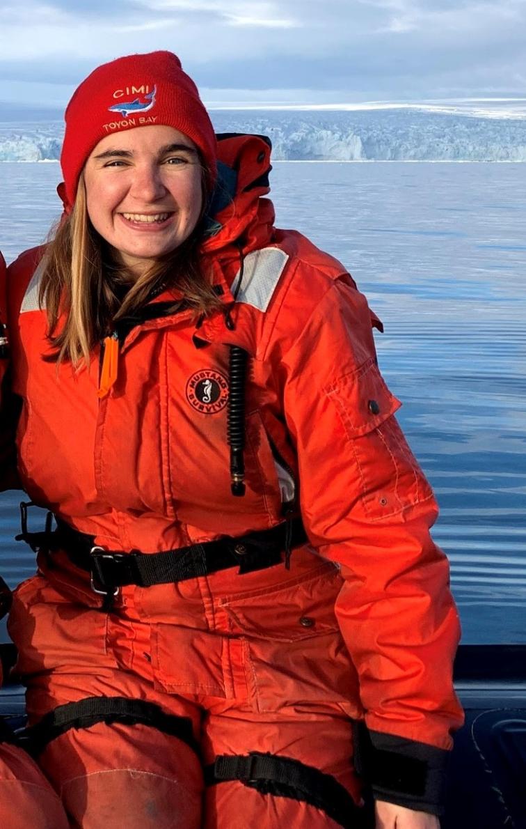 A woman in a bright orange survival suit on a small boat